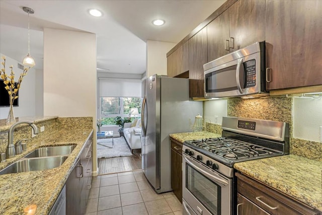 kitchen with stainless steel appliances, light stone countertops, sink, and light tile patterned floors