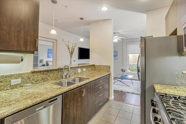 kitchen featuring light tile patterned flooring, sink, light stone counters, hanging light fixtures, and stainless steel appliances