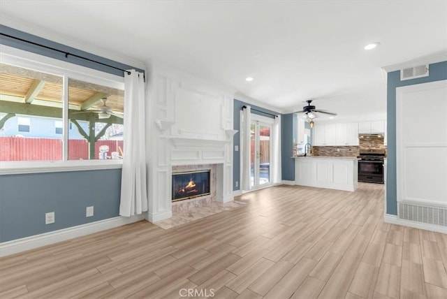 unfurnished living room with a healthy amount of sunlight, a premium fireplace, and light hardwood / wood-style floors