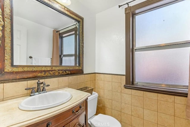 bathroom with toilet, vanity, and tile walls