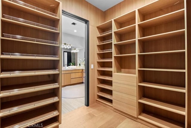 walk in closet with light hardwood / wood-style floors