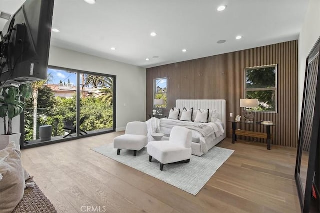 bedroom featuring access to outside, wooden walls, and light hardwood / wood-style floors