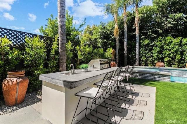 view of patio with an outdoor kitchen, a bar, and grilling area