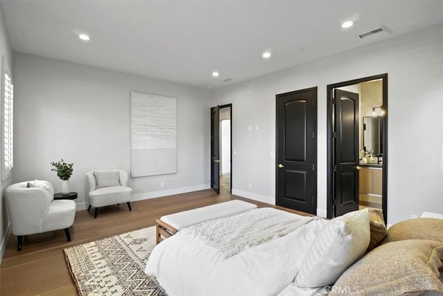 bedroom featuring multiple windows, connected bathroom, and hardwood / wood-style flooring