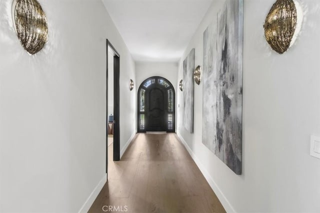 hallway featuring dark wood-type flooring and a notable chandelier