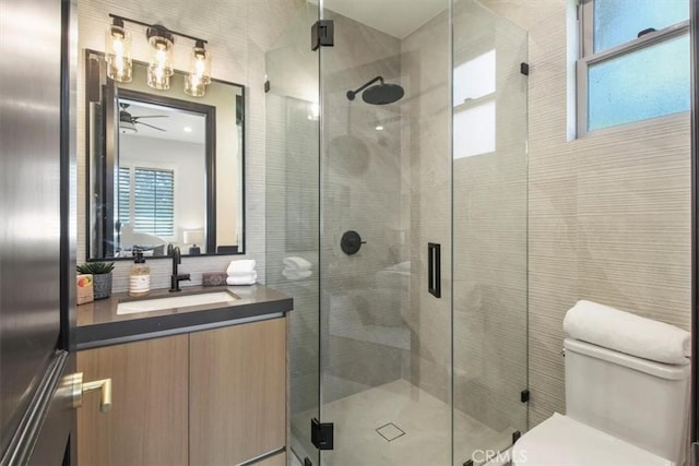 bathroom with ceiling fan, vanity, an enclosed shower, and toilet