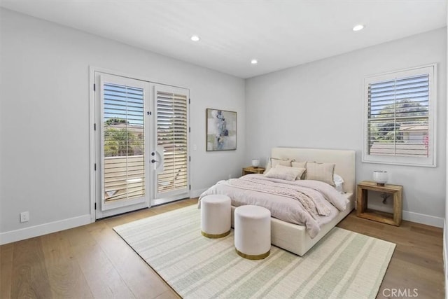 bedroom with hardwood / wood-style floors, access to exterior, french doors, and multiple windows