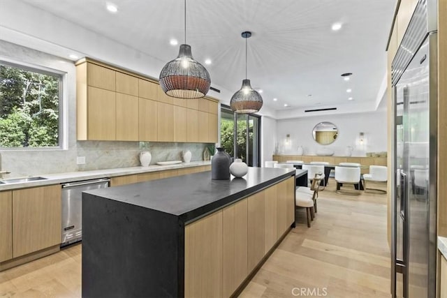 kitchen featuring a kitchen island, decorative light fixtures, stainless steel appliances, light hardwood / wood-style floors, and light brown cabinetry