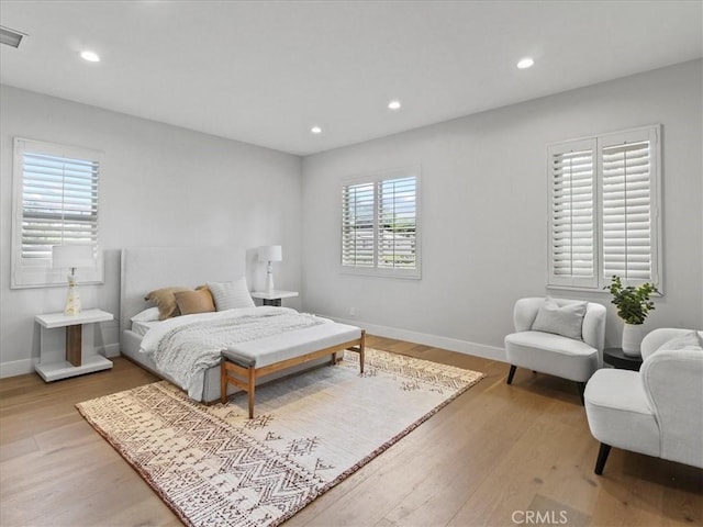 bedroom with multiple windows and hardwood / wood-style floors