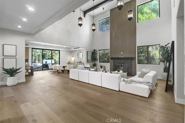 living room with a high ceiling, a large fireplace, beamed ceiling, and hardwood / wood-style floors