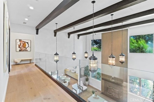 hall with a wealth of natural light, hardwood / wood-style flooring, and beamed ceiling