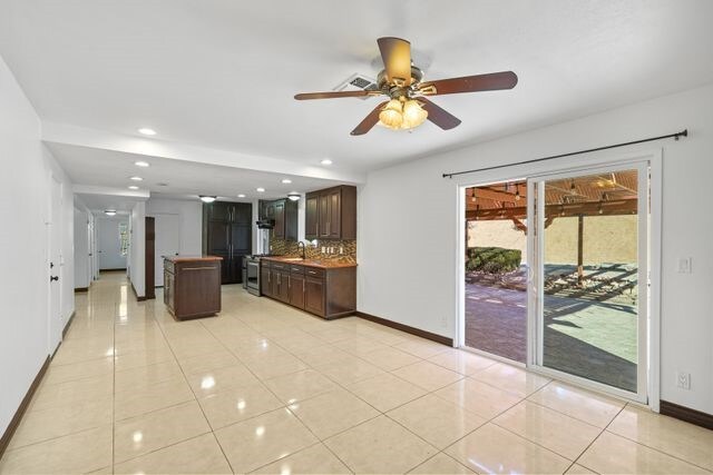 kitchen with ceiling fan, light tile patterned floors, dark brown cabinets, and a center island