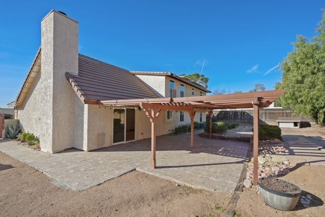 rear view of property featuring a pergola and a patio area