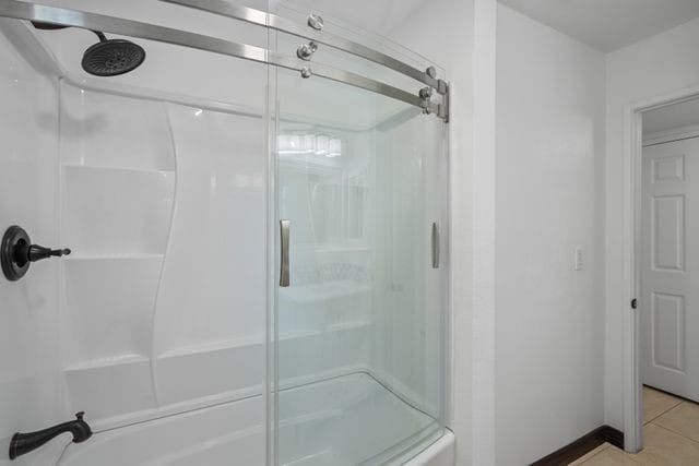 bathroom with tile patterned floors and shower / bath combination with glass door