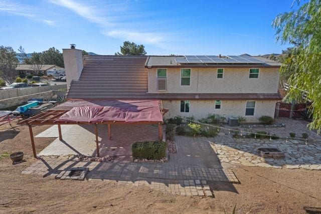 rear view of property featuring cooling unit, a patio area, and solar panels