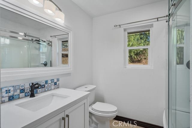 bathroom with an enclosed shower, vanity, and toilet