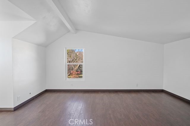 additional living space with dark hardwood / wood-style flooring and vaulted ceiling with beams