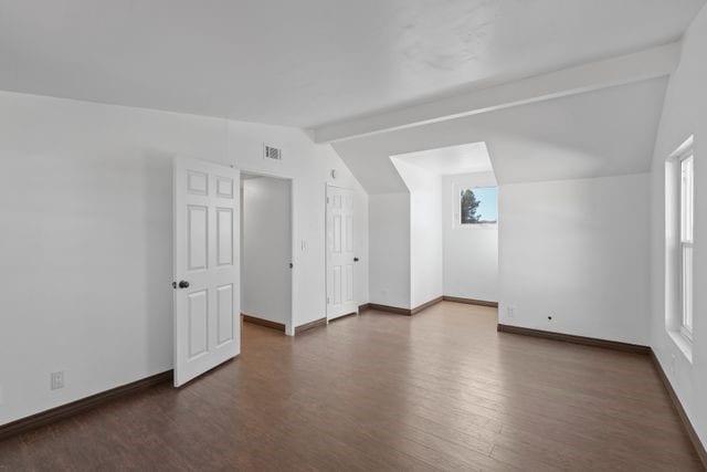 additional living space with dark hardwood / wood-style floors and lofted ceiling with beams