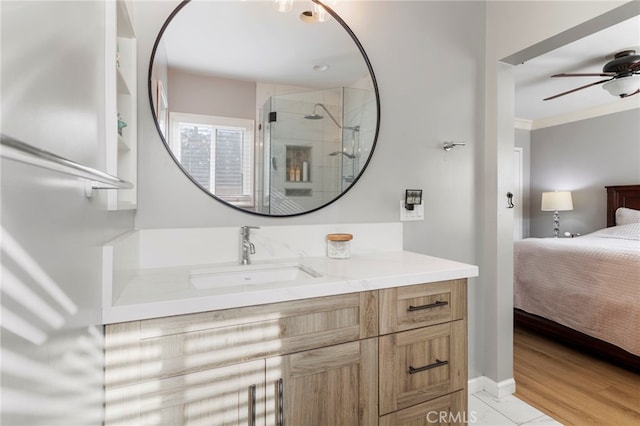 bathroom featuring ceiling fan, vanity, wood-type flooring, ornamental molding, and an enclosed shower