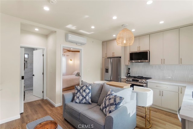 living room with a wall mounted AC and light hardwood / wood-style floors