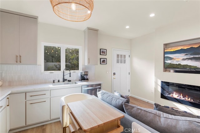 kitchen featuring light hardwood / wood-style floors, wooden counters, backsplash, dishwasher, and sink