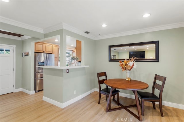 dining space featuring light wood-type flooring and ornamental molding