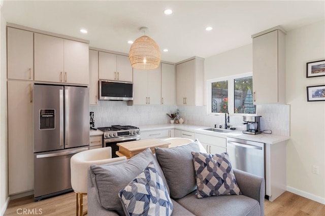 kitchen featuring decorative light fixtures, sink, stainless steel appliances, and light hardwood / wood-style floors