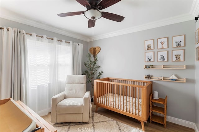 bedroom featuring ceiling fan, hardwood / wood-style flooring, ornamental molding, and a crib