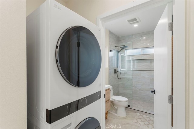 bathroom with tile patterned floors, a shower with door, stacked washer / drying machine, vanity, and toilet