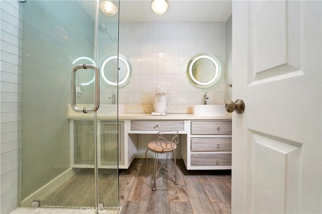 bathroom with a shower with shower door, hardwood / wood-style floors, and vanity