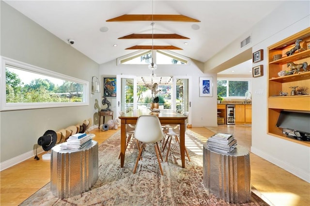 dining room featuring beverage cooler, light hardwood / wood-style flooring, and lofted ceiling with beams