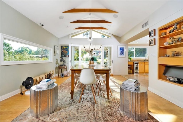 dining space featuring lofted ceiling with beams, wine cooler, light hardwood / wood-style floors, and built in shelves