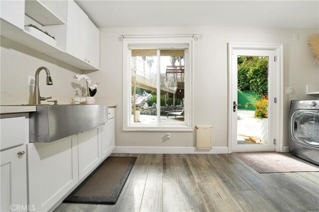 doorway with washer / clothes dryer, plenty of natural light, sink, and hardwood / wood-style flooring