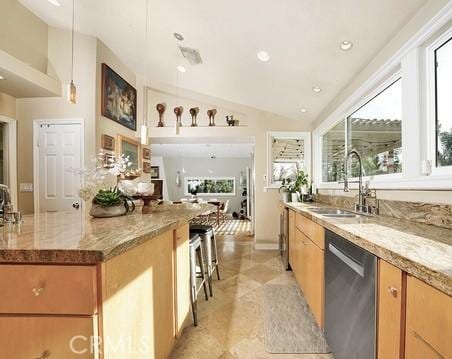 kitchen with lofted ceiling, sink, decorative light fixtures, stainless steel dishwasher, and light stone countertops