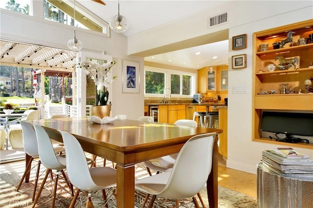 dining area with wine cooler, sink, lofted ceiling, and light wood-type flooring