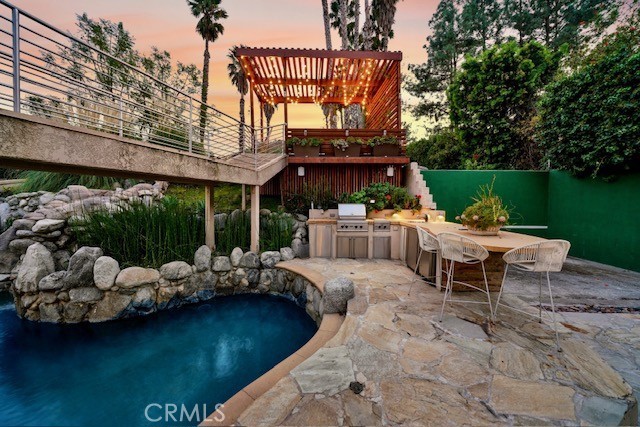 pool at dusk with a patio, area for grilling, and grilling area