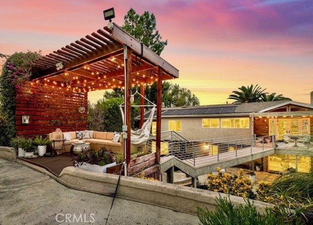 deck at dusk with outdoor lounge area and a pergola