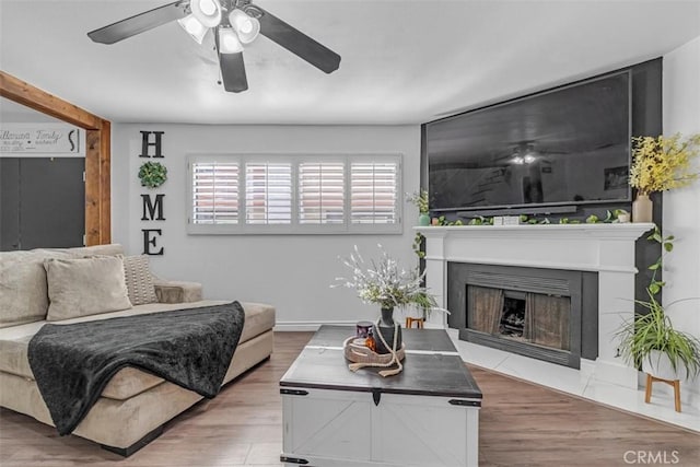 living room featuring ceiling fan, beam ceiling, and light wood-type flooring