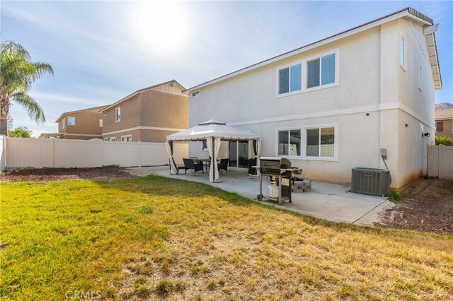 rear view of house with a gazebo, cooling unit, a patio area, and a lawn