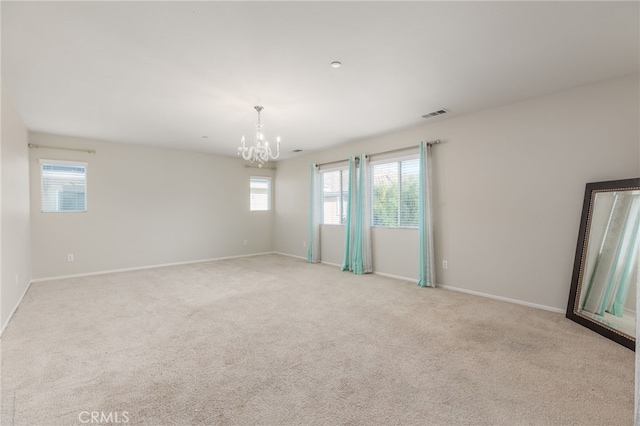 unfurnished room featuring light colored carpet, plenty of natural light, and a chandelier