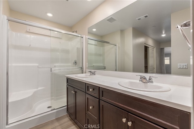 bathroom with vanity, a shower with shower door, and hardwood / wood-style floors