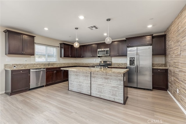 kitchen with dark brown cabinetry, appliances with stainless steel finishes, hanging light fixtures, and light hardwood / wood-style flooring