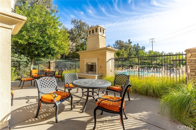 view of patio with an outdoor fireplace and a fenced in pool