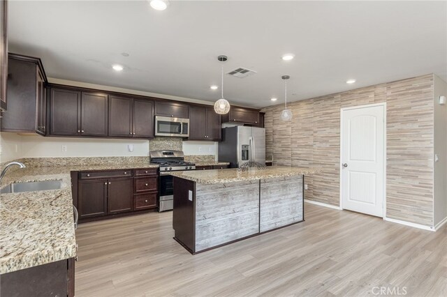 kitchen featuring a kitchen island, pendant lighting, sink, light hardwood / wood-style floors, and stainless steel appliances