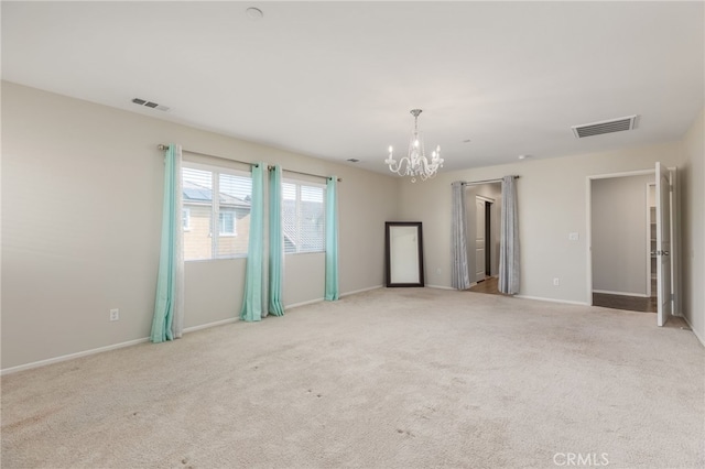 carpeted empty room featuring an inviting chandelier