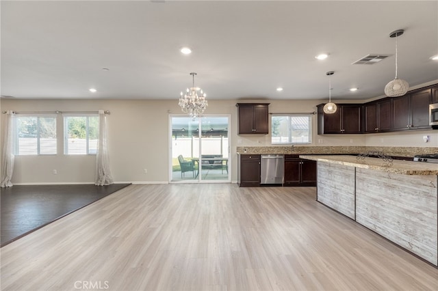 kitchen with appliances with stainless steel finishes, hanging light fixtures, dark brown cabinets, light stone counters, and light wood-type flooring