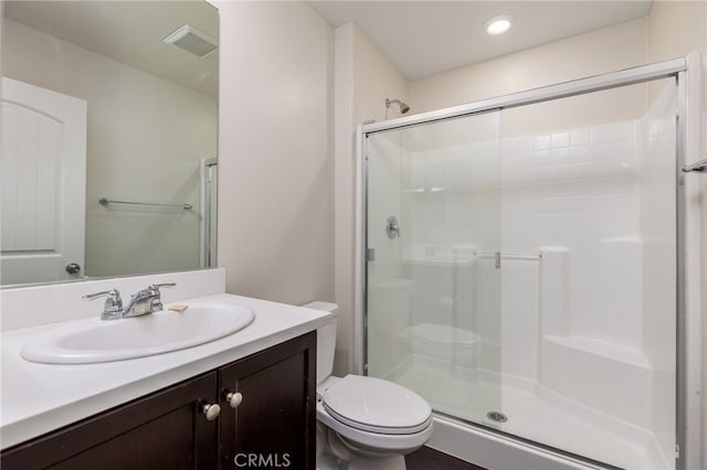 bathroom with vanity, a shower with door, and toilet