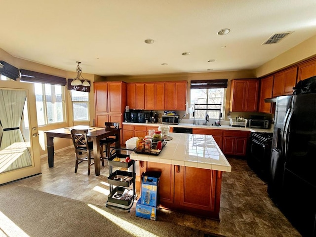 kitchen featuring dark carpet, appliances with stainless steel finishes, tile counters, decorative light fixtures, and a center island