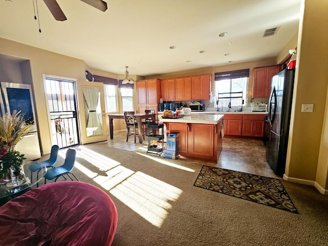 kitchen with decorative light fixtures, a wealth of natural light, appliances with stainless steel finishes, and a center island