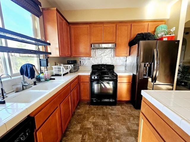 kitchen with black appliances, sink, backsplash, and tile counters